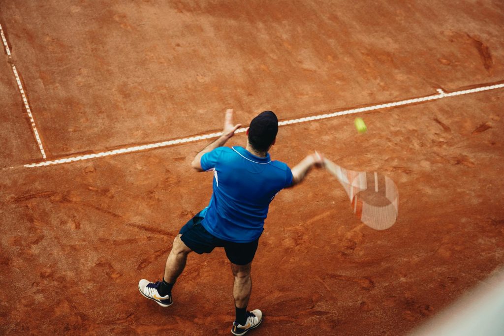 Tay vợt trượt người đánh forehand trên sân đất nện